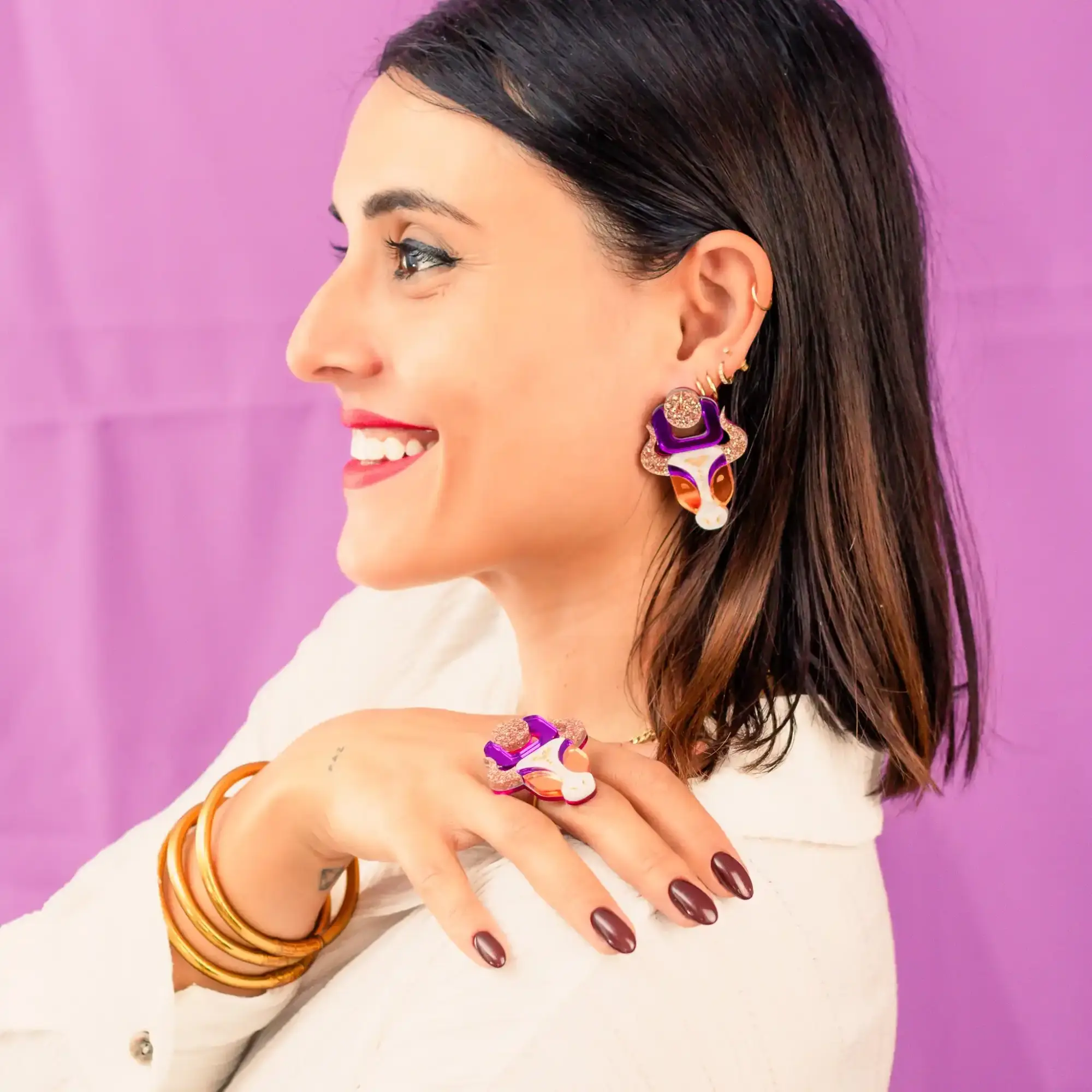 Modelo luciendo los pendientes Vaca Sagrada India, con diseño en metacrilato espejo, detalles de glitter y nácar pintados a mano, perfectos para un look llamativo y elegante